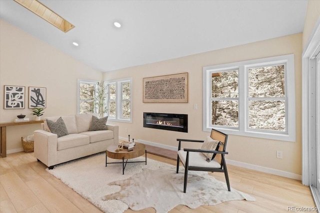 interior space featuring baseboards, a glass covered fireplace, wood finished floors, vaulted ceiling, and recessed lighting