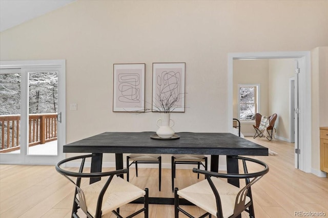 dining space featuring light wood-style floors and vaulted ceiling