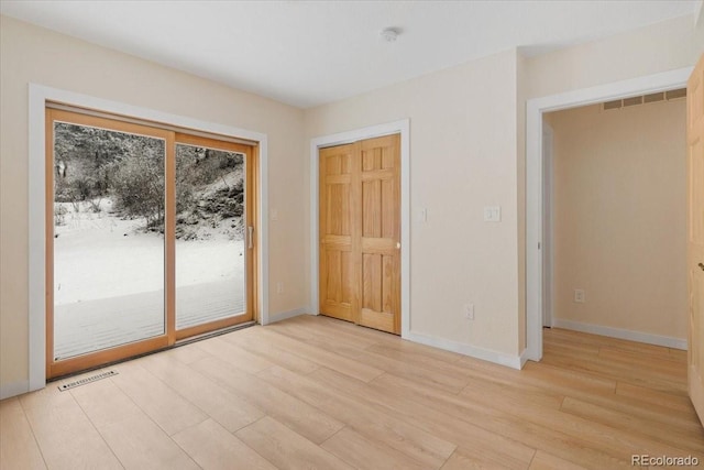 unfurnished bedroom with light wood-style floors, access to outside, visible vents, and baseboards