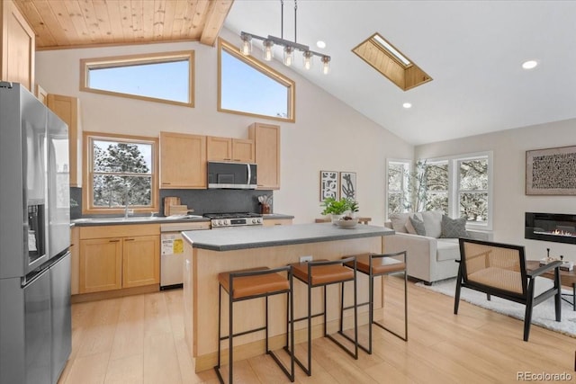 kitchen featuring a center island, a wealth of natural light, appliances with stainless steel finishes, light wood-style floors, and light brown cabinets