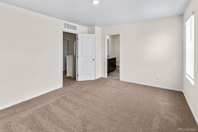 unfurnished bedroom featuring visible vents, baseboards, connected bathroom, and carpet flooring