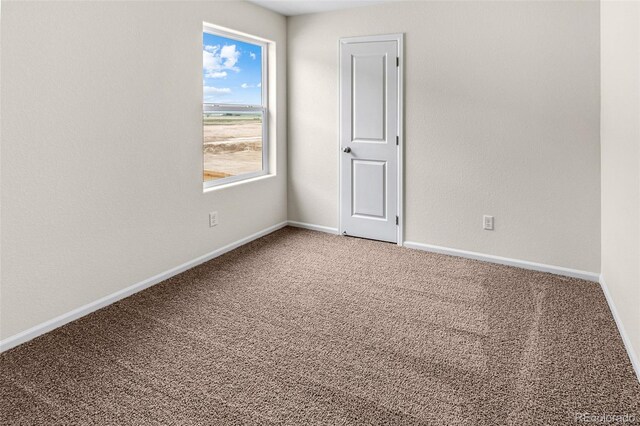 carpeted spare room featuring baseboards