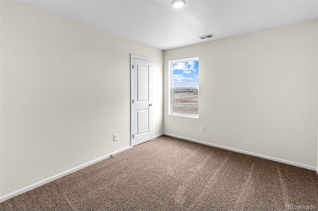 carpeted empty room with visible vents, a textured ceiling, and baseboards