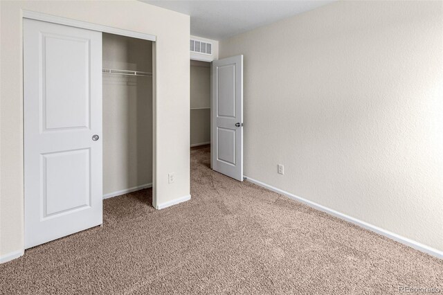 unfurnished bedroom featuring a closet, visible vents, baseboards, and carpet