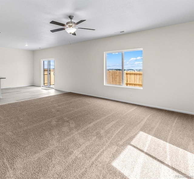 carpeted empty room featuring visible vents, baseboards, and ceiling fan