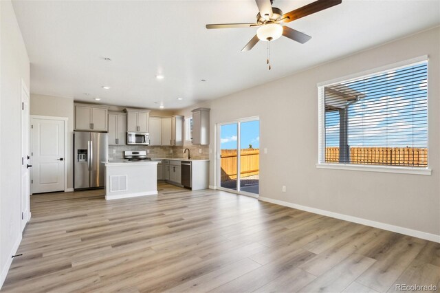 17943 E 94th Pl, Commerce City, CO 80022 - kitchen with appliances with stainless steel finishes, gray cabinets, open floor plan, light countertops, and tasteful backsplash