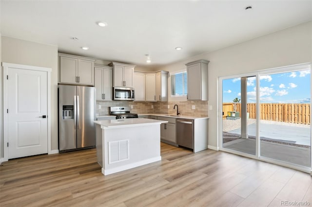 17943 E 94th Pl, Commerce City, CO 80022 - kitchen featuring appliances with stainless steel finishes, gray cabinetry, backsplash, light countertops, and light wood finished floors