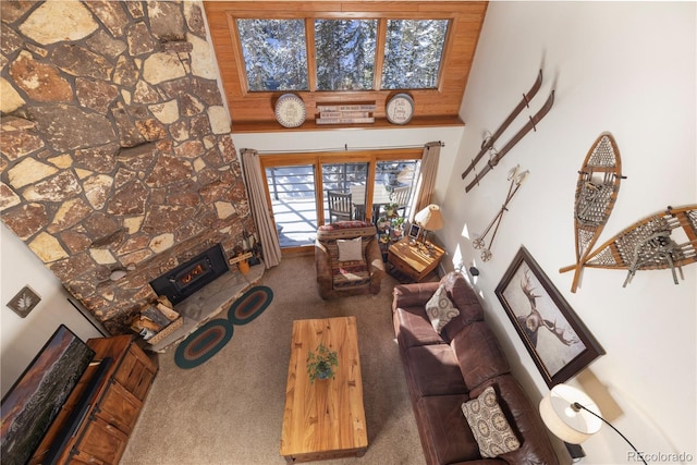 carpeted living area with a warm lit fireplace and a towering ceiling