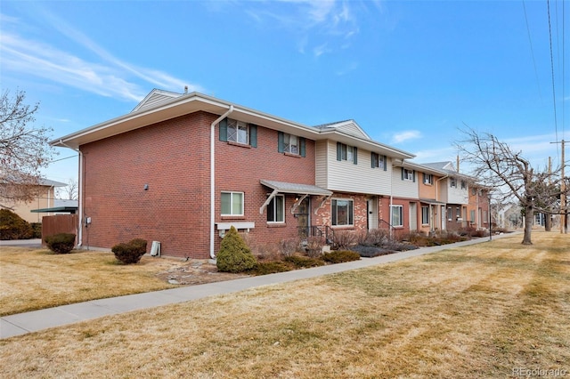 view of side of home featuring brick siding and a yard