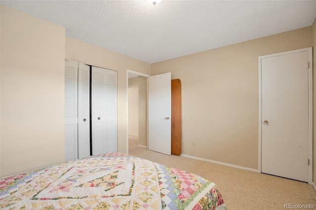 bedroom featuring a textured ceiling, baseboards, light colored carpet, and a closet