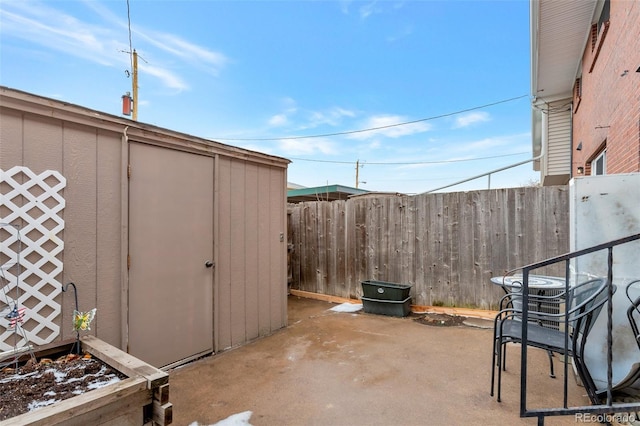 view of patio / terrace with a storage shed, fence, and an outdoor structure