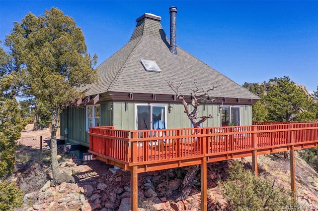 rear view of property with a deck and a shingled roof