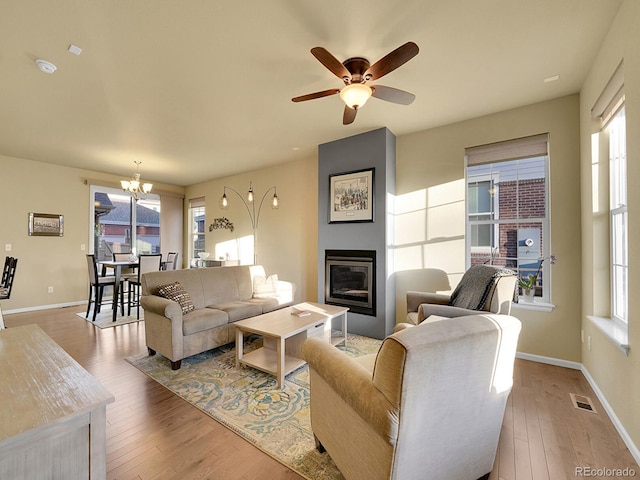 living room featuring a large fireplace, light wood-style flooring, plenty of natural light, and visible vents