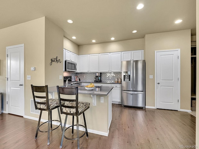 kitchen featuring appliances with stainless steel finishes, white cabinetry, dark wood-type flooring, and a breakfast bar area