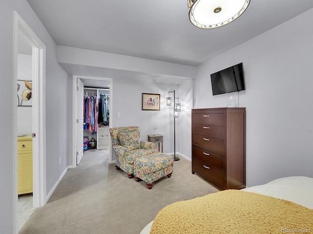 bedroom featuring a walk in closet, a closet, light carpet, and baseboards