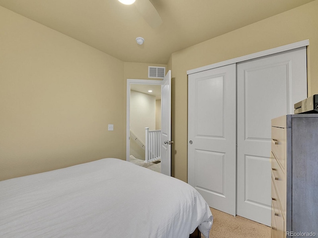 bedroom featuring a closet, visible vents, ceiling fan, and light carpet