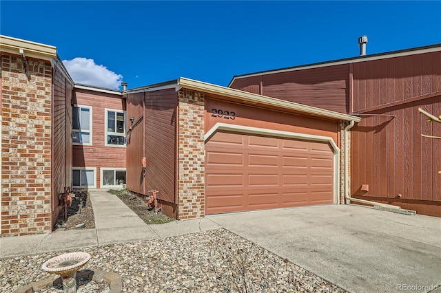 view of front facade with a garage, driveway, and brick siding