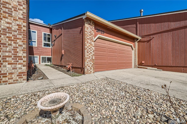 view of side of property with a garage, brick siding, and driveway