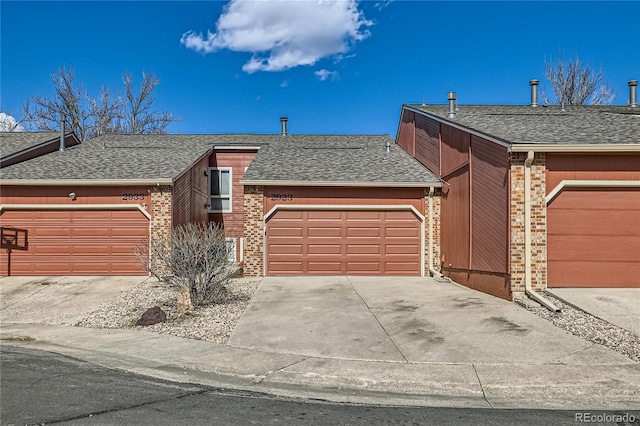 view of front of house with a garage, driveway, a shingled roof, and brick siding