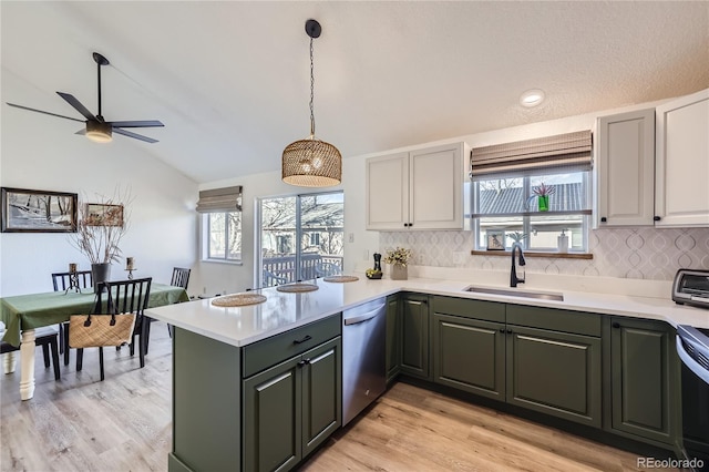 kitchen with plenty of natural light, dishwasher, a peninsula, light countertops, and a sink