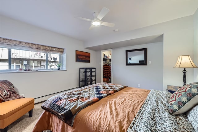 carpeted bedroom featuring a baseboard heating unit, a spacious closet, a closet, and ceiling fan