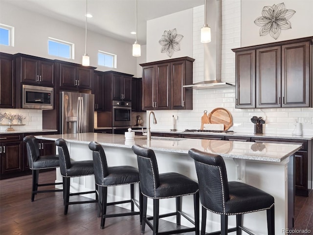 6970 E Lake Dr, Centennial, CO 80111 - kitchen with decorative backsplash, decorative light fixtures, appliances with stainless steel finishes, a sink, and wall chimney exhaust hood