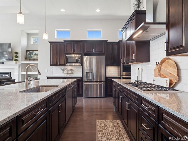 6970 E Lake Dr, Centennial, CO 80111 - kitchen featuring wall chimney range hood, dark brown cabinetry, a sink, light stone counters, and stainless steel appliances