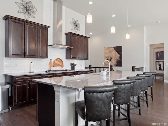 6970 E Lake Dr, Centennial, CO 80111 - kitchen featuring decorative backsplash, a sink, light stone counters, dark wood-style floors, and wall chimney exhaust hood