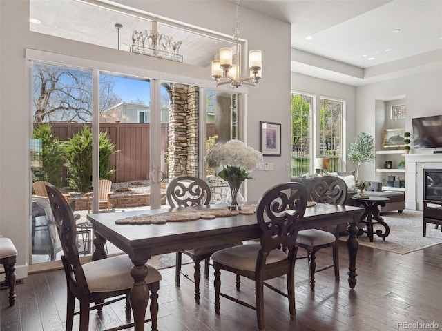 6970 E Lake Dr, Centennial, CO 80111 - dining room featuring a notable chandelier, a glass covered fireplace, built in shelves, recessed lighting, and dark wood-style floors