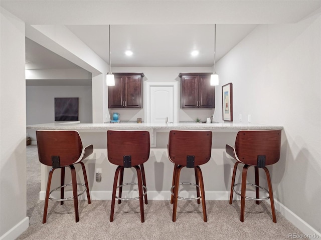 6970 E Lake Dr, Centennial, CO 80111 - kitchen with dark brown cabinets, light colored carpet, light countertops, baseboards, and a kitchen bar