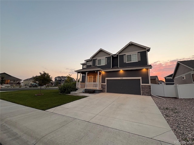 view of front of property featuring a lawn, covered porch, and a garage