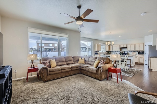 living room featuring a textured ceiling, ceiling fan with notable chandelier, and dark wood-type flooring