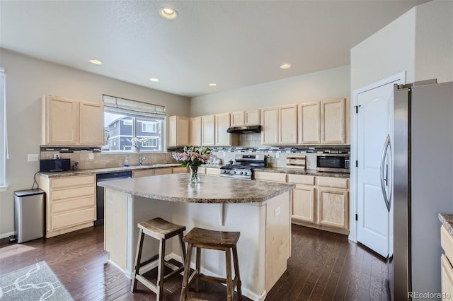 kitchen with backsplash, a kitchen breakfast bar, appliances with stainless steel finishes, a kitchen island, and dark hardwood / wood-style flooring