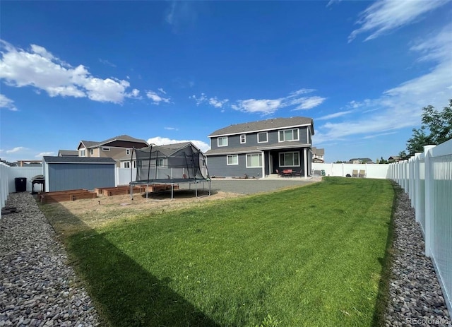 rear view of house with a yard and a trampoline