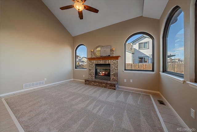 unfurnished living room with a brick fireplace, ceiling fan, vaulted ceiling, and light tile patterned floors