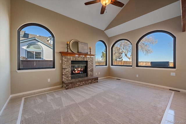 unfurnished living room featuring ceiling fan, a brick fireplace, high vaulted ceiling, and light tile patterned floors