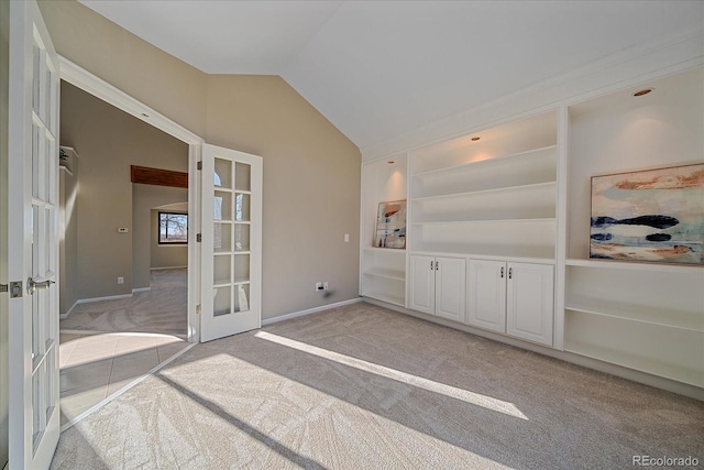 interior space with lofted ceiling, french doors, and light carpet