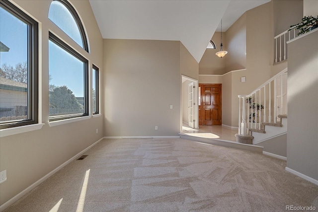 interior space with light carpet and a towering ceiling