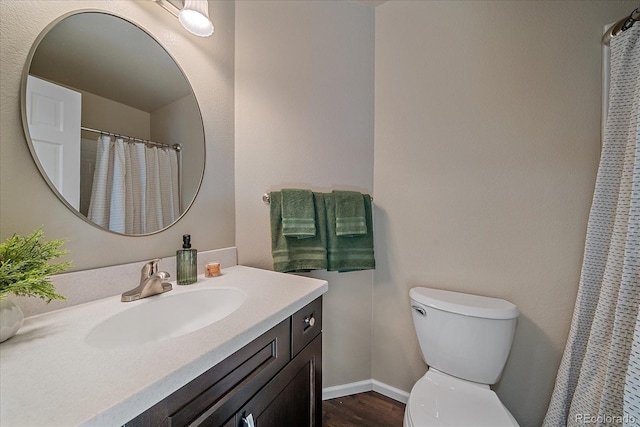 bathroom with toilet, vanity, and hardwood / wood-style floors