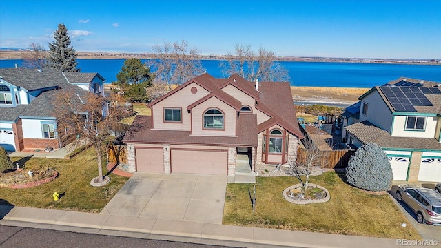 view of front of house with a garage, a water view, and a front lawn