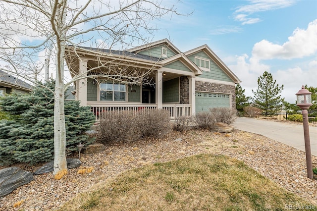 craftsman house with a porch, an attached garage, stone siding, and driveway