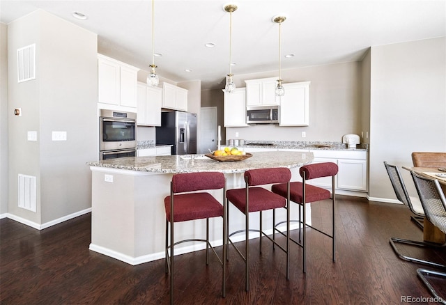 kitchen featuring stainless steel appliances, visible vents, dark wood-style flooring, and a kitchen island