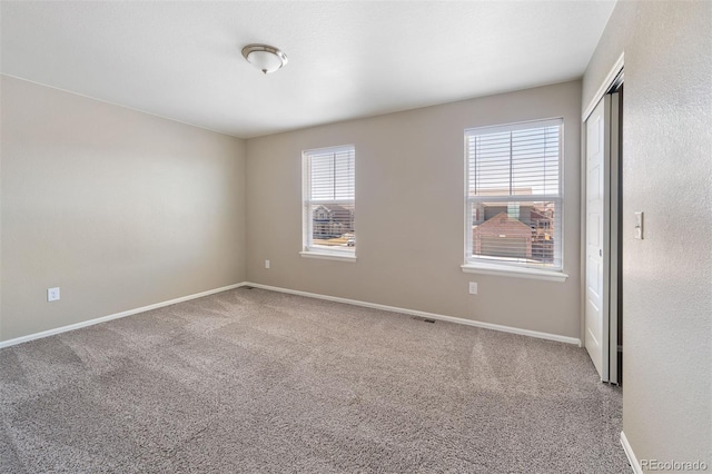 unfurnished bedroom with a closet, carpet, visible vents, and baseboards