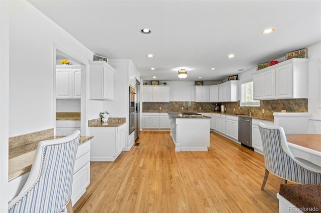 kitchen with appliances with stainless steel finishes, sink, white cabinetry, and light wood-type flooring