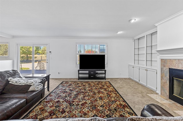 living room featuring crown molding, a tiled fireplace, light colored carpet, and plenty of natural light