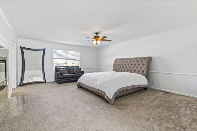 carpeted bedroom featuring ceiling fan, crown molding, and a fireplace