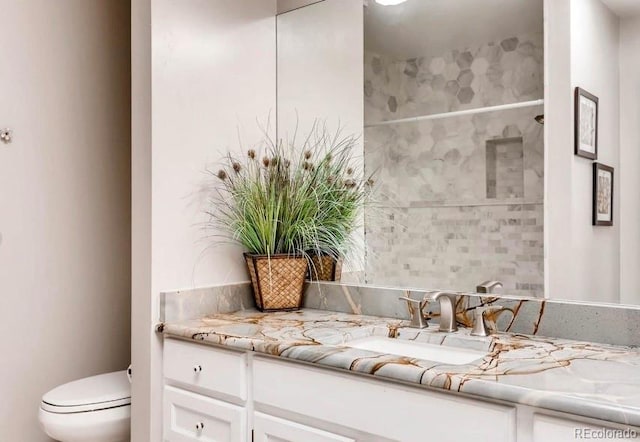 bathroom with vanity, toilet, and a tile shower