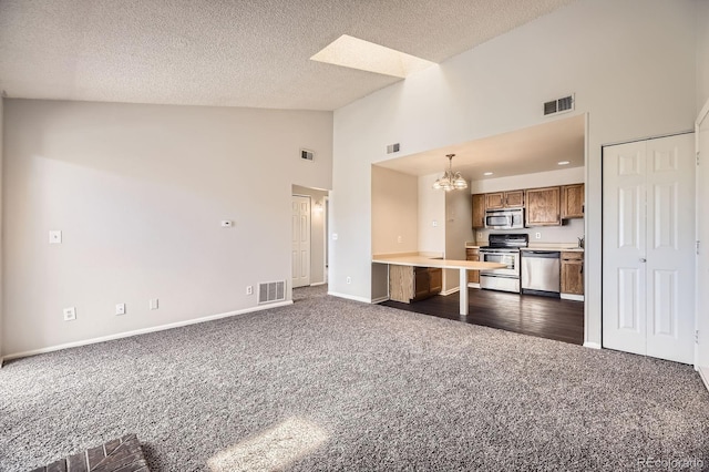 4899 S Dudley St Unit 20G, Littleton, CO 80123 - kitchen featuring appliances with stainless steel finishes, dark colored carpet, high vaulted ceiling, brown cabinetry, and open floor plan
