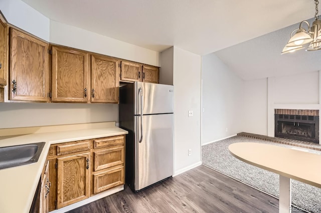 4899 S Dudley St Unit 20G, Littleton, CO 80123 - kitchen with freestanding refrigerator, a fireplace, brown cabinetry, open floor plan, and light countertops