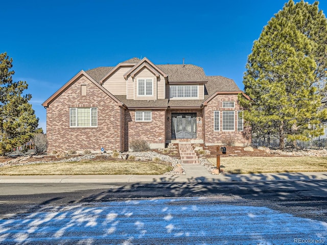 view of front of property with brick siding and roof with shingles